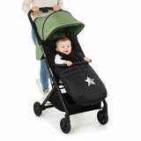 Baby in a black and green stroller with a star design on a white background