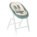 Baby high chair with green cushion and white stand on a white background