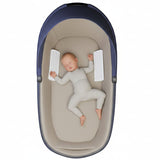 Baby lying in a blue and beige baby carrycot on a white background