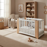 Set of four wooden cribs with white panels on a white background