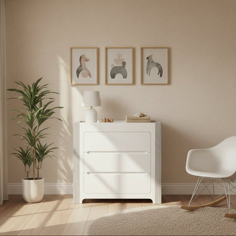 Modern interior design with a white dresser, chair, and plant in a room with neutral walls and flooring.