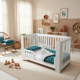 White crib with blue and white bedding featuring animal patterns on a white background
