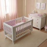 White crib with pink floral crib sheet and bumper on a white background