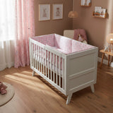 Crib with pink floral and animal patterned bedding set on a white background